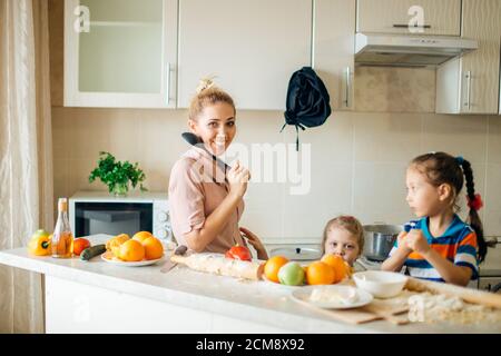 Kleiner Bruder und Schwester kochen eine Mahlzeit beide Rühren der Inhalt des gleichen Topfes, der von ihrem Lachen bewacht wird Junge Mutter Stockfoto