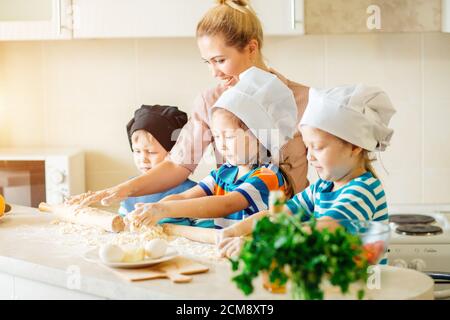 Junge Familie kochen in der Küche. Fröhliches junges Mädchen mit ihrer Mutter, der Teig in der Schüssel mischen. Stockfoto