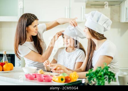 Glückliche Familie in der Küche. Mutter und Töchter bereiten Teig, backen Cookies Stockfoto