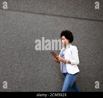 Porträt einer lächelnden afrikanerin, die mit einem Tablet durch die Stadt geht Stockfoto