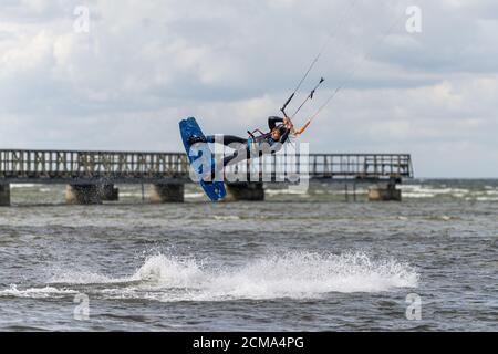 Malmö, Schweden - 23. August 2020: Ein Kitesurfer springt hoch ins Wasser an einem windigen Tag, an dem viele Leute die Gelegenheit nutzen, Wassersport zu üben Stockfoto