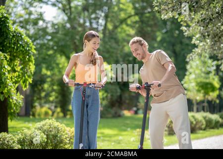 Junge glückliche Paar Roller im Park reiten und genießen Der Tag Stockfoto