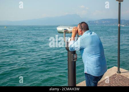 Der Mensch schaut auf das Fernglas am Gardasee Stockfoto