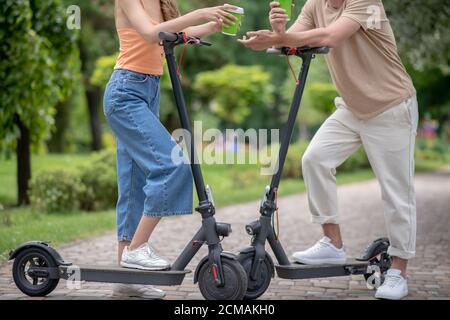 Zwei Personen mit Motorroller reden im Park Stockfoto