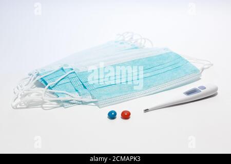 Medizinische Einweg-Gesichtsmaske. Thermometer, rote Tablette, blaue Tablette. Selektiver Fokus Stockfoto
