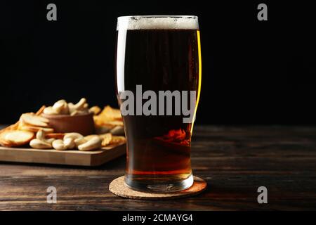 Ein Glas Bier und Snacks auf einem Holztisch Stockfoto