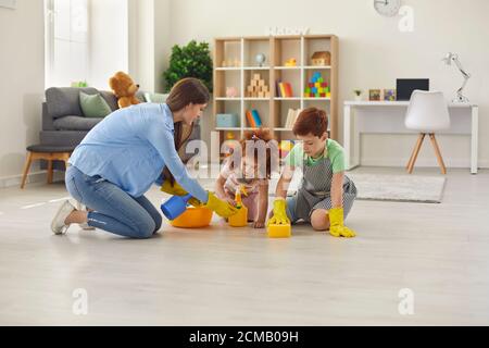 Happy Family putzt Zimmer mit Handschuhen. Mutter, Sohn und Tochter putzen das Haus. Stockfoto