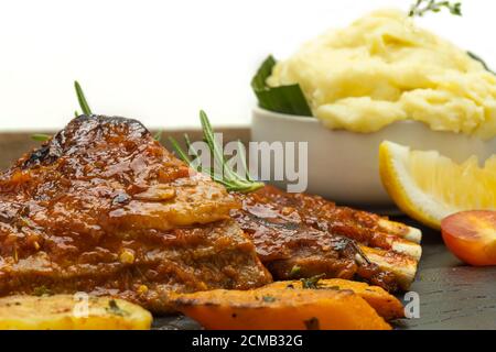 Geröstete Schweinsrippen mit Kartoffelpüree und gerösteten Tomaten auf weißem Hintergrund. Stockfoto