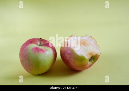 Ein ganzer Apfel und ein gebissene Apfel liegen auf einem farbigen Hintergrund. Nahaufnahme Stockfoto