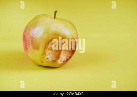 Ein gebissene Apfel liegt auf einem farbigen Hintergrund. Nahaufnahme Stockfoto