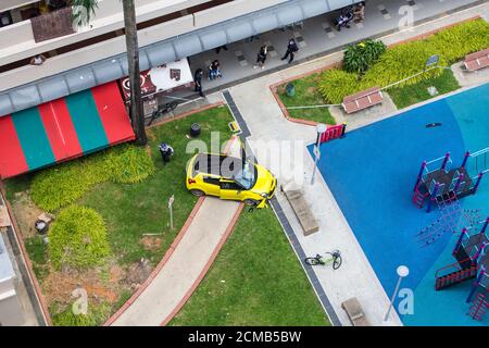 Aus der Vogelperspektive stürzte das gelbe Suzuki-Fahrzeug auf den öffentlichen Gehweg. Eine Verkehrspolizei und Zuschauer beobachten seltsame Situationen. Singapur. Stockfoto