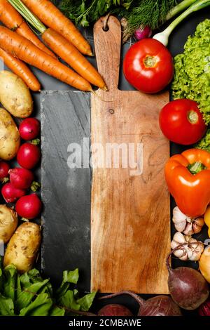 Rahmen aus frischen reifen Gemüse sortiert um Schneidebrett Nahaufnahme: Tomaten, Karotten, Paprika, Rüben, Karotten, Knoblauch Stockfoto