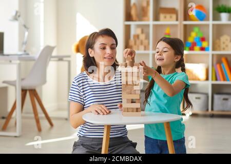 Mutter und Tochter spielen und bauen Turm aus Holz Blöcke in gemütlichen Kindergarten zu Hause Stockfoto