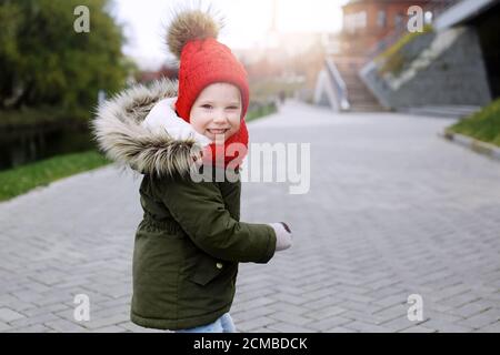 Süße kleine lustige Mädchen in trendigen Outfit zu Fuß auf der Straße, Spaß haben, lachen, Blick auf die Kamera Stockfoto