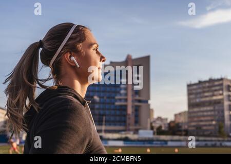 Frau läuft im Stadion, Nahaufnahme. Weibliche Läuferin Training im Freien im Profil. Gesundes Lifestyle-Bild der jungen kaukasischen Frau joggen draußen. Stockfoto