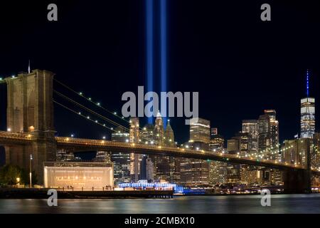 9/11 Tribute im Licht. Brooklyn Bridge und Lower Manhattan bei Nacht beleuchtet. Blick vom Main Street Park. Stockfoto