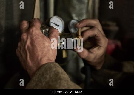 Hände eines Mannes, der mit einem Manometer in der Garage arbeitet, Nahaufnahme. Stockfoto