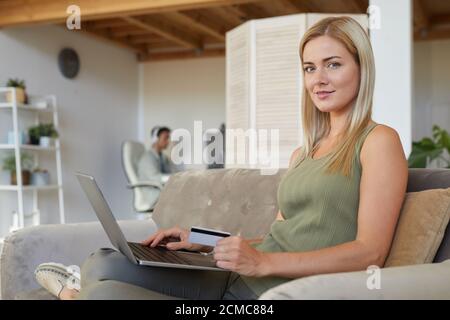 Porträt der jungen Frau auf dem Sofa mit Laptop und sitzen Online arbeiten im Wohnzimmer zu Hause Stockfoto