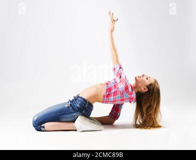 Junge moderne tanzende Mädchen in Jeans auf grau Stockfoto