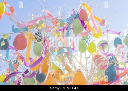 Bunte helle ostereier mit Bändern hängen am Baum. Ostern festliche Hintergrund Stockfoto