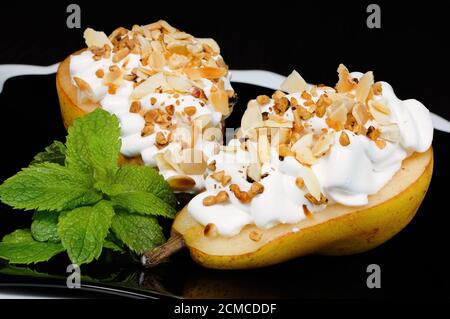 Birne mit Schlagsahne und Nüssen Stockfoto