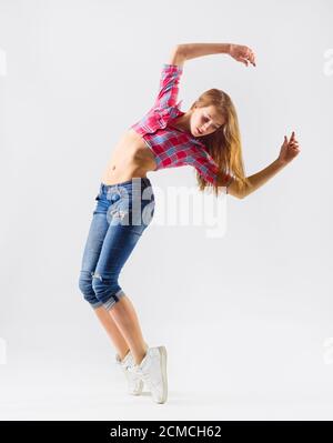 Junge moderne tanzende Mädchen in Jeans auf grau Stockfoto