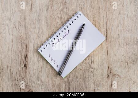 Business- und Bürokonzept - leeres Notizbuch und schwarzer Stift auf Holztisch. Ziele 2019. Minimal flach liegend, Draufsicht. Stockfoto