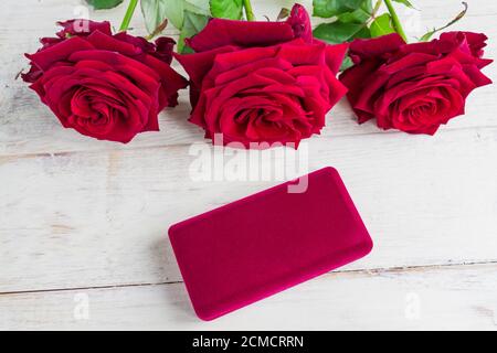 Schmuckschatulle und wunderschöne rote Rosen auf Holzhintergrund. Stockfoto