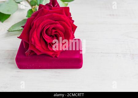 Schmuckschatulle und wunderschöne rote Rose auf Holzhintergrund. Stockfoto