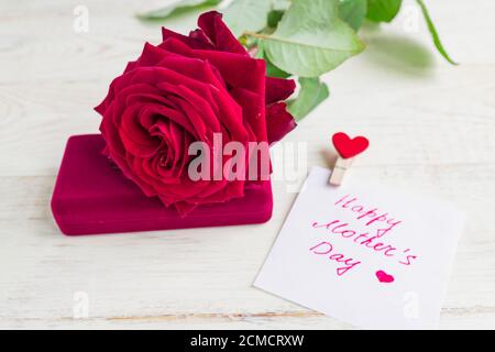 Schmuckschatulle und wunderschöne rote Rose auf Holzhintergrund. Grußkarte zum Muttertag Stockfoto
