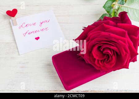 Schmuckschatulle und wunderschöne rote Rose auf Holzhintergrund. Stockfoto