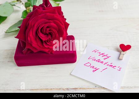 Schmuckschatulle und wunderschöne rote Rose auf Holzhintergrund. Geschenk zum Valentinstag Stockfoto