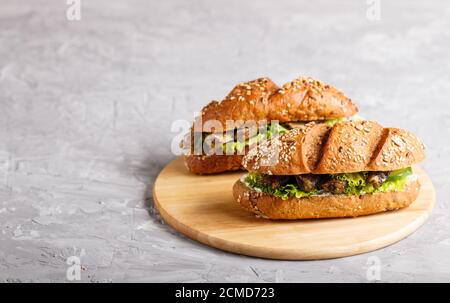 Sprotte Sandwiches mit Salat und Frischkäse auf Holzbrett auf grauem Beton Hintergrund. Seitenansicht, Kopierraum, selektiver Fokus. Stockfoto