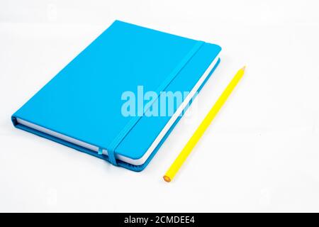 Blaues Notizbuch und gelber Bleistift auf weißem Hintergrund. Designkonzept Stockfoto