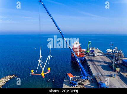 16. September 2020, Mecklenburg-Vorpommern, Vierow: Ein Kran hebt ein Modell einer Anlage mit schwimmenden Windkraftanlagen im Hafen ins Wasser. (Luftaufnahme mit Drohne) die Testanlage ist im Greifswalder Bodden verankert. Das Energieunternehmen EnBW und der Schleswig-holsteinische Windturbinenhersteller Aerodyn Engineering wollen nun Nezzy2 im Meer mit Wellen testen. Das Forschungsprojekt umfasst eine neue Offshore-Technologie, in der die Windenergieanlagen auf dem Wasser schwimmen. Bislang sind Offshore-Turbinen fest auf Stahlrahmen im Meeresboden verankert. Die Modellanlage ist mit t ausgestattet Stockfoto