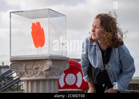 Ein Passant sieht sich eine Arbeit von Maureen Jordan an der Uferpromenade von Folkestone im Rahmen des neuen Kunstprojekts von Creative Folkestone namens The Plinth an – platziert 10 freie Sockel an verschiedenen Orten in der Küstenstadt und lädt Bewohner und Besucher dazu ein, sie zu nutzen, um ihre künstlerischen Talente zu zeigen, Anlässlich der Neuinstallation von Art Buff, einem Gemälde des Straßenkünstlers Banksy, auf der Old High Street von Folkestone. Stockfoto