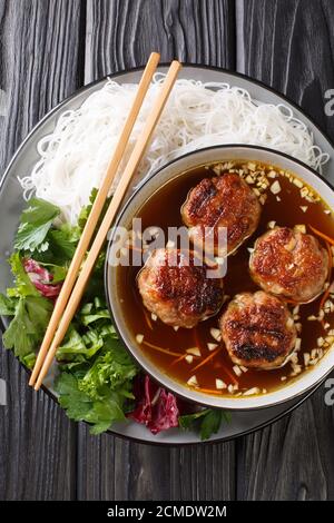 Bun Cha ist ein vietnamesisches Gericht aus gegrilltem Schweinefleisch, Nudel und Kräuter Nahaufnahme in der Platte auf dem Tisch. Vertikale Draufsicht von oben Stockfoto