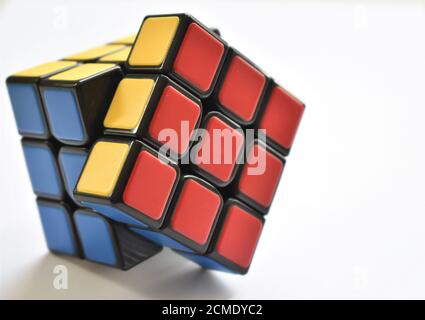 Ein isoliertes Rubik's Cube Puzzle sitzt fast auf einem gelöst Gestochen scharfer weißer Hintergrund bei hellem, natürlichem Licht Stockfoto