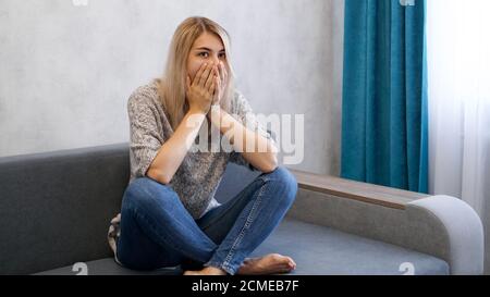 Hübsche blonde Frau bedeckt den Mund mit Händen mit einem schockiert, sieht sie besorgt oder verängstigt. Stockfoto