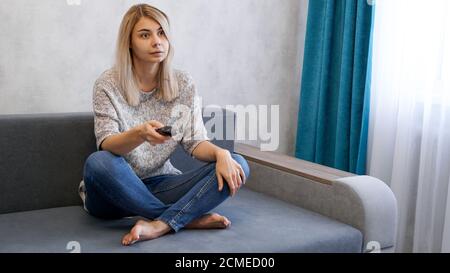 Junge schöne Frau Fernsehen auf der Couch im Wohnzimmer Überrascht und aufgeregt Stockfoto