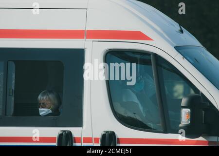 Split Kroatien September 2020 Weißer Ambulanzwagen von der Seite gesehen, wie es vorbeigeht. Drei Sanitäter in der Vorderseite tragen Gesichtsmasken, ältere Dame sitzt Stockfoto