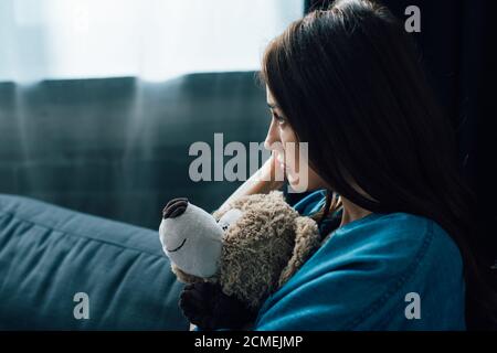 Deprimierte Brünette Frau hält Teddybär beim Blick weg Stockfoto