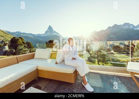 Junge Frau auf dem Balkon bei Holzhaus in Ruhe Die Landschaft Stockfoto