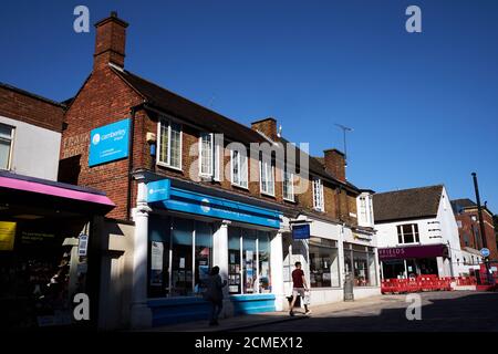 Ein Mitglied der Öffentlichkeit geht an Camberley Travel vorbei, die Ist geöffnet und ein geschlossener ehemaliger Thomas Cook Laden in Camberley Stadtzentrum Stockfoto