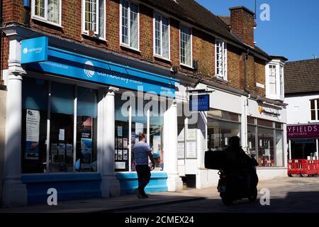 Ein Mitglied der Öffentlichkeit geht an Camberley Travel vorbei, die Ist geöffnet und ein geschlossener ehemaliger Thomas Cook Laden in Camberley Stadtzentrum Stockfoto