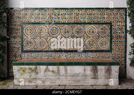 Alcazar von Sevilla, Spanien. Bank mit Keramikfliesen (Azulejos) in einem Innenhof dekoriert Stockfoto