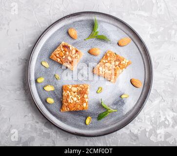 Traditionelle arabische Süßigkeiten in grauer Keramik-Platte auf grauem Beton-Hintergrund. Draufsicht, Nahaufnahme. Stockfoto