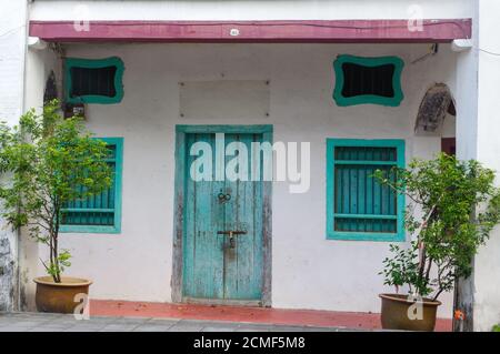 Haus in George Town, Penang, Malaysia. Außen im mediterranen Stil. Blaue Holztüren und Fensterläden an alten bemalten Wänden Stockfoto