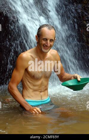 Glücklicher Mann, Prospektor, der Gold in einen Fluss mit Schleusenkasten schwenkt Stockfoto