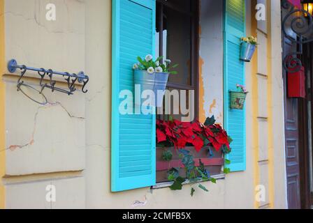 Weiße Steinfassade mit blauen Fensterläden und Blumen aus der Seite Stockfoto